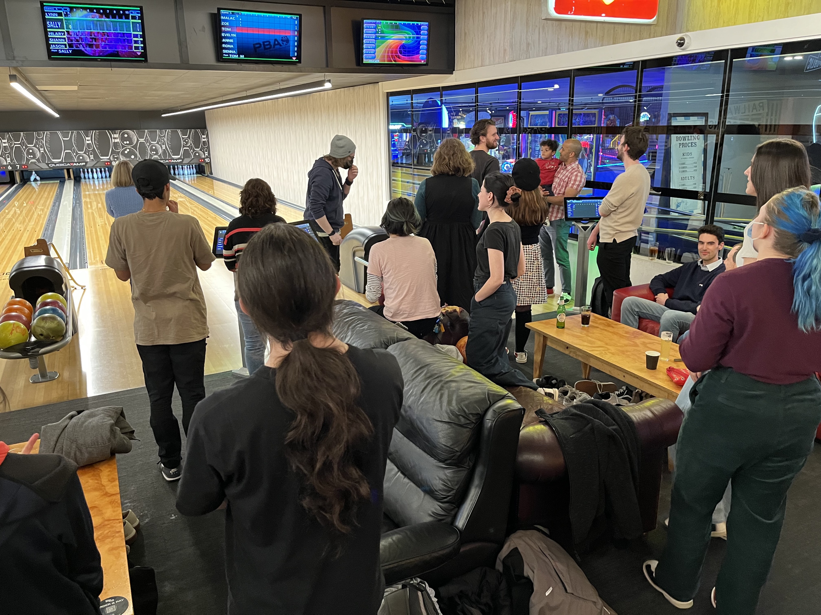 People from the Information Access Group at a bowling alley taking turns at bowling. In the background are the bowling lanes, and in the foreground is the lounge area where people socialise and wait to bowl. Click to view full image.