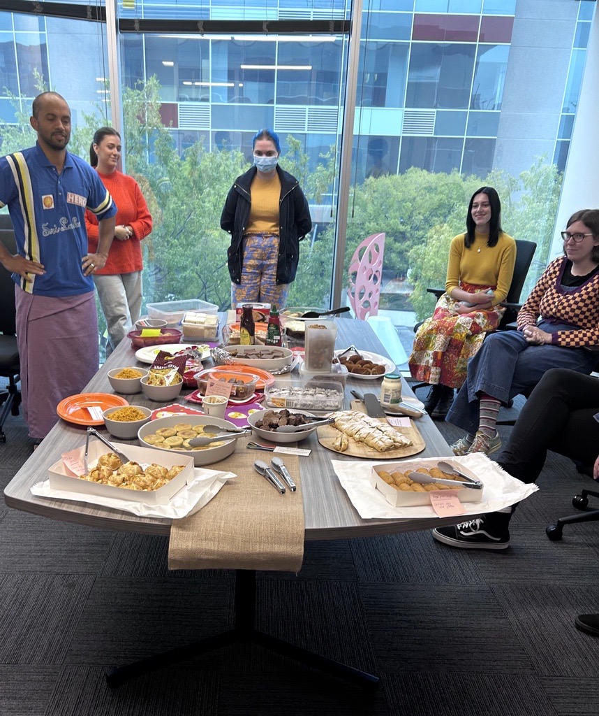 People from the Information Access Group standing and sitting around the conference table, celebrating Harmony Day. On the table is a large collection of food that people have brought in from their different cultures. Pictured in the photograph are Sean, Savanah, Zoe, Sienna, and Renee. Click to view full image.