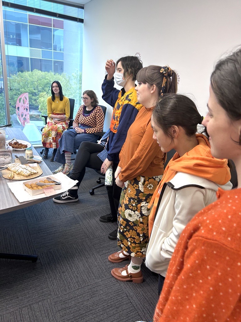 People from the Information Access Group standing near the conference table, celebrating Harmony Day. Food is laid out on the table. Pictured in the photograph are Evelyn, Shannon, Mikayla, Annie, Renee, and Sienna. Click to view full image.