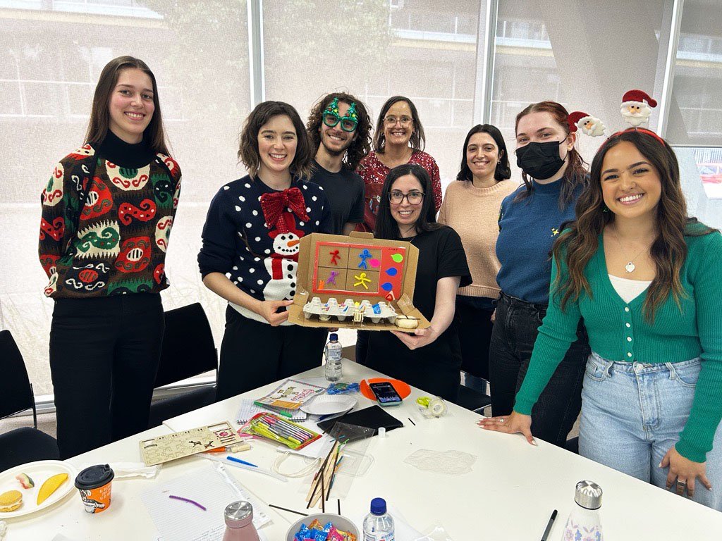 People from the Information Access Group smiling at the camera, taking part in the Information Access Group values session. 2 people are holding up a diorama of a Teams call on a laptop. In front of them is a table covered in different craft supplies. Pictured in the photograph are Sienna, Annie, Edward, Kellie, Myriam, Sarah, Zoe, and Taylah. Click to view full image.